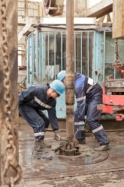 Muddy workers on drill rig