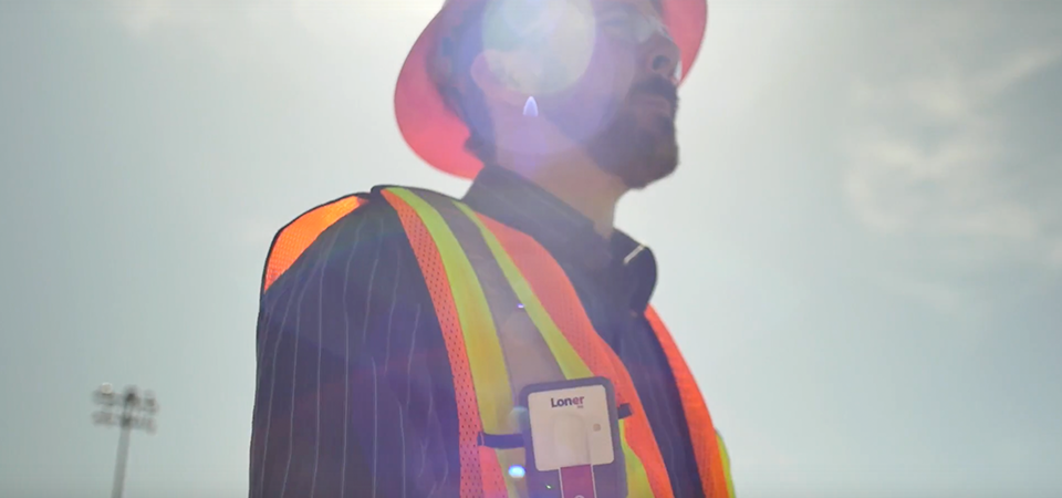 Blackline Safety Loner M6-apparaat voor alleenwerkers, gedragen door een werknemer die in de hete zon werkt